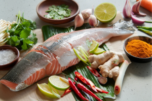 A plate of fresh rawas fillets surrounded by ingredients for preparing asian style steamed fish.