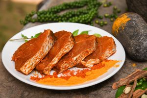 A plate of fresh seer or vanjaram fillets marinated and surrounded by ingredients for preparing vanjaram meen fish fry.