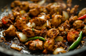 Pan of boneless chicken frying with onions and green chillies for ultimate chicken sukka recipe