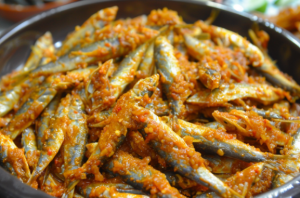 A wide bowl of fresh nethili fish marinated in rice flour, chilly powder and other spices for preparing nethili fish dry recipe.