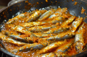 Sizzling pan of marinated nethili fish frying in oil for nethili fish dry recipe