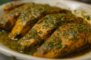 A plate of fresh tilapia fillets marinated in fresh spices& herbs for preparing steamed fish recipe.