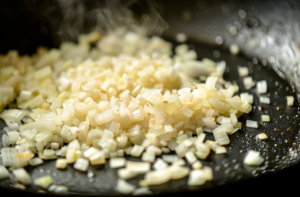 A sizzling pan of finely chopped onions for making pepper chicken.