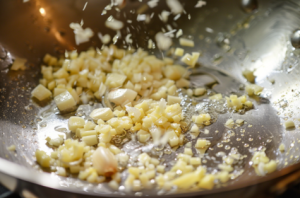 A close-up of a sizzling pan with chopped garlic being sautéed in melted butter for garlic butter chicken recipe