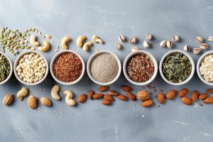 Assorted nuts and seeds in small bowls lined up- to get the right nutrition and avoid overeating