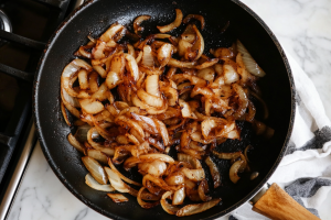 A pan filled with golden-brown onions frying in hot oil, sizzling and turning crisp for mutton curry or bhune pyaaz ka gosht