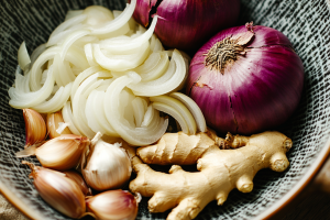 Ingredients for Thai coconut chicken soup, including onions, ginger, and shallots arranged neatly