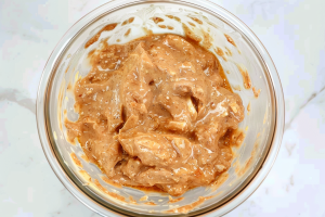 A bowl of chicken pieces marinating in Indian spices and yoghurt, preparing for the Chicken 65 dish.